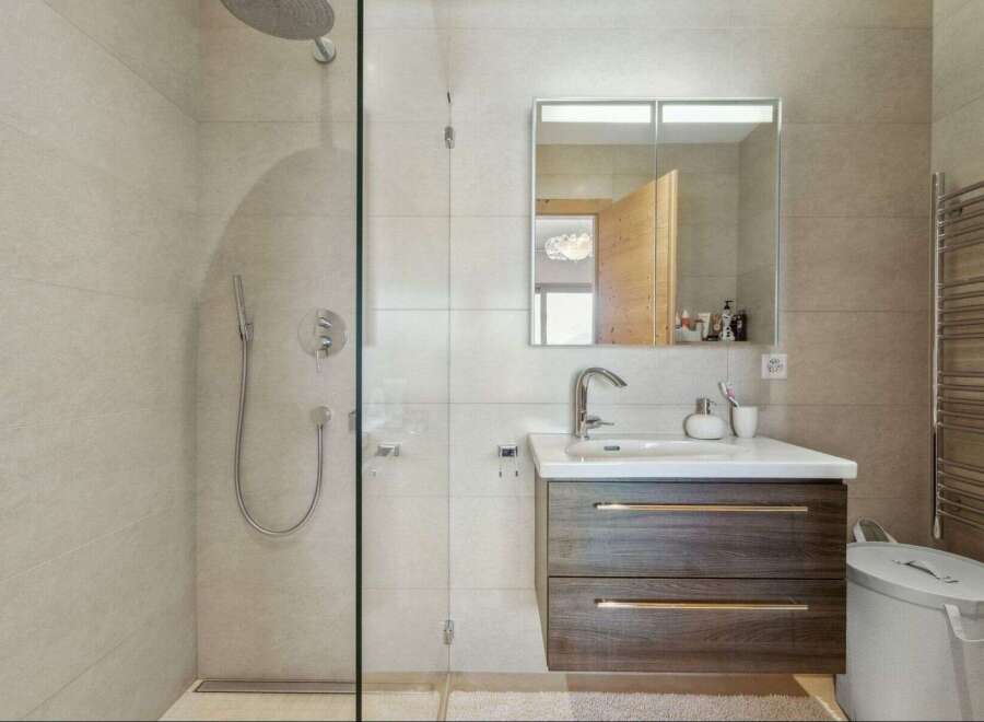 Step into this modern bathroom, featuring a sleek glass shower enclosure and stylish vanity.
