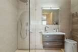 Step into this modern bathroom, featuring a sleek glass shower enclosure and stylish vanity.