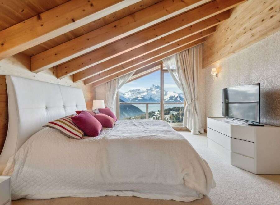 Experience luxury living in this stunning bedroom with breathtaking mountain views.