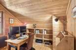 This charming home office features a warm, inviting atmosphere with its wooden walls and sloped ceiling.