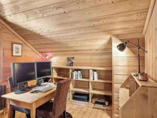 This charming home office features a warm, inviting atmosphere with its wooden walls and sloped ceiling.