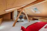 This stunning attic bedroom boasts a unique architectural design with exposed wooden beams and a sloped ceiling, creating a warm and inviting atmosphere.