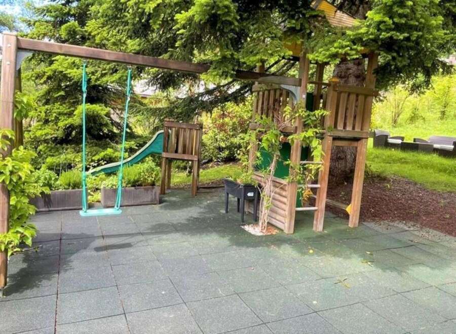 Discover the perfect outdoor oasis for your family! This property boasts a charming playground, complete with a swing set and a fun slide, nestled amidst lush greenery.