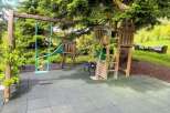 Discover the perfect outdoor oasis for your family! This property boasts a charming playground, complete with a swing set and a fun slide, nestled amidst lush greenery.