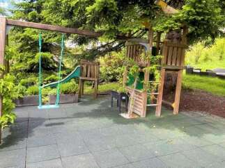 Discover the perfect outdoor oasis for your family! This property boasts a charming playground, complete with a swing set and a fun slide, nestled amidst lush greenery.