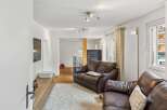 Step into this inviting living space, featuring a cozy leather sofa and a plush, white rug.