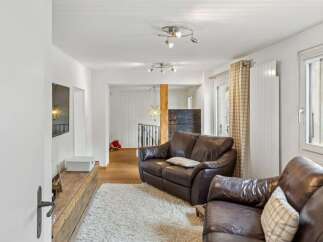 Step into this inviting living space, featuring a cozy leather sofa and a plush, white rug.