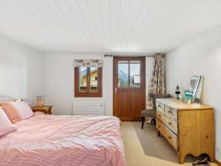 Discover the charm of this cozy bedroom, featuring a rustic wooden door and a window offering stunning mountain views.