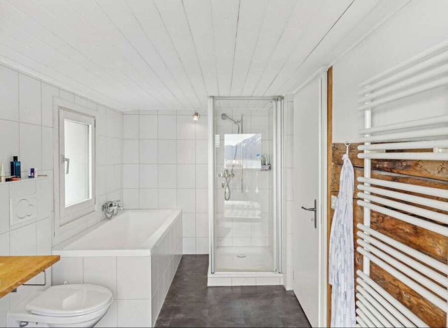 This modern bathroom features a sleek design with white tiles and a glass shower enclosure.