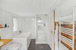 This modern bathroom features a sleek design with white tiles and a glass shower enclosure.