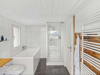 This modern bathroom features a sleek design with white tiles and a glass shower enclosure.