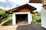 This charming property features a detached garage with a unique wooden roof design, offering both functionality and aesthetic appeal.