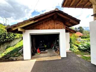 This charming property features a detached garage with a unique wooden roof design, offering both functionality and aesthetic appeal.