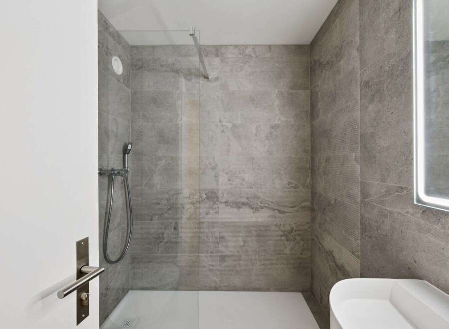 Step into a modern bathroom oasis! This stunning space features sleek gray tile, a glass shower enclosure, and a contemporary sink.