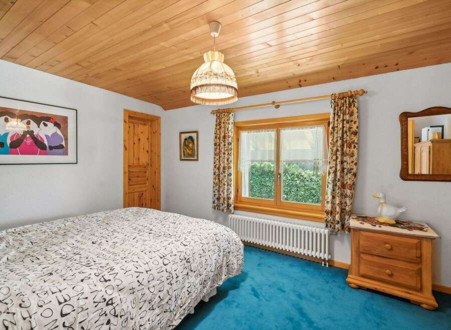 Step into this charming bedroom featuring a cozy wooden ceiling and a vibrant blue carpet.