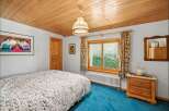 Step into this charming bedroom featuring a cozy wooden ceiling and a vibrant blue carpet.