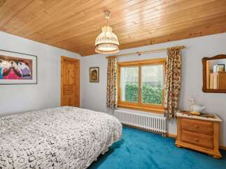 Step into this charming bedroom featuring a cozy wooden ceiling and a vibrant blue carpet.
