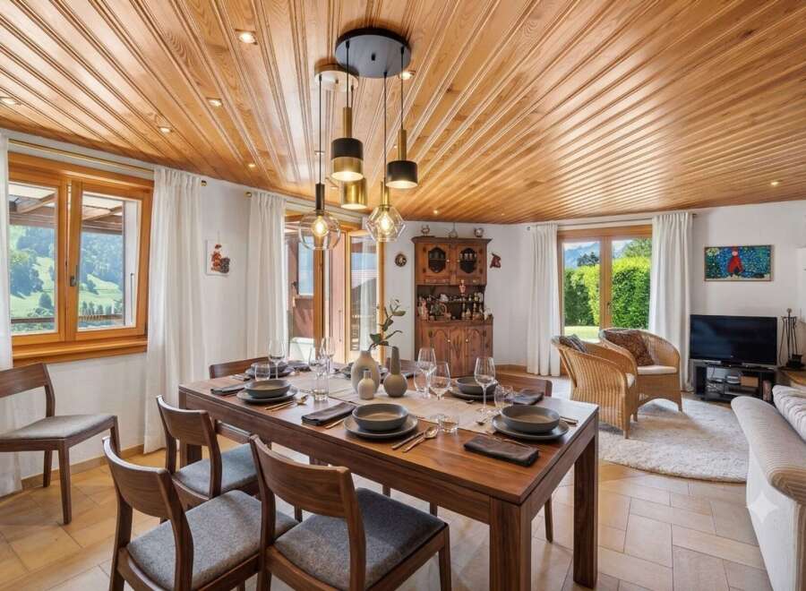 Experience elegant dining in this beautifully appointed room, featuring a rich wooden dining table set for a feast and surrounded by comfortable chairs.
