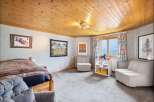 This charming bedroom features a cozy wooden bed, complemented by a soft grey carpet and a wood-paneled ceiling.