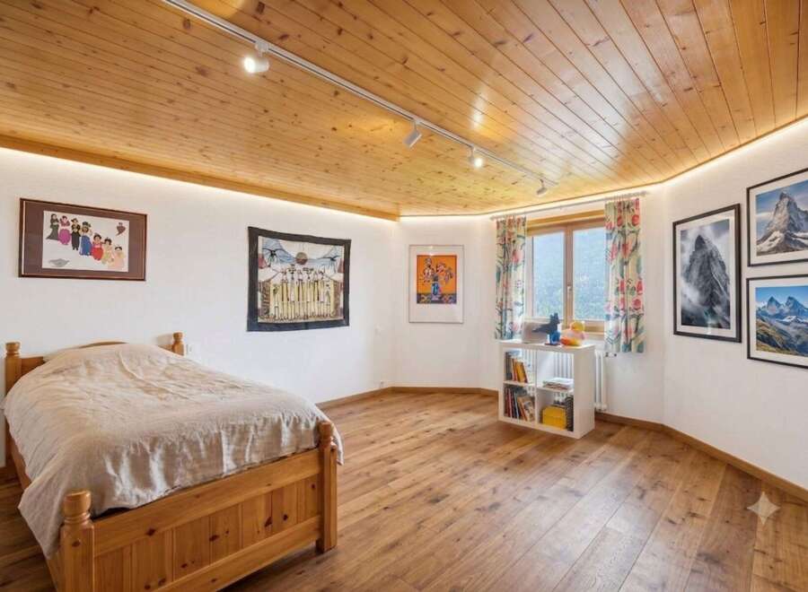 Experience cozy mountain living in this charming bedroom featuring a warm wooden ceiling and floors.