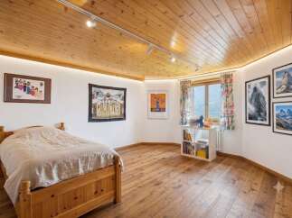 Experience cozy mountain living in this charming bedroom featuring a warm wooden ceiling and floors.