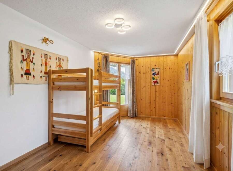 This charming bedroom features a cozy wooden bunk bed, perfect for families or guests.