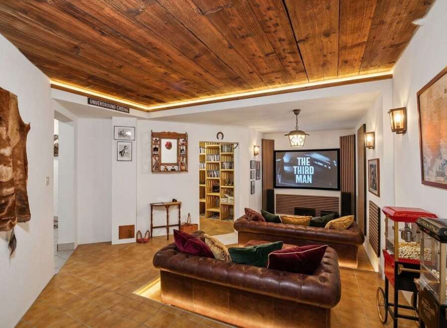 Experience cinematic entertainment in this unique basement media room, featuring plush leather sofas and a large screen perfect for movie nights.