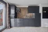 This modern kitchen boasts sleek, dark cabinetry and a stunning mosaic tile backsplash, creating a sophisticated and stylish space.