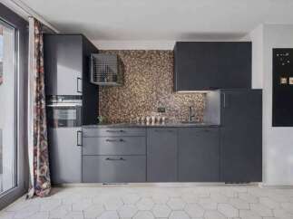 This modern kitchen boasts sleek, dark cabinetry and a stunning mosaic tile backsplash, creating a sophisticated and stylish space.