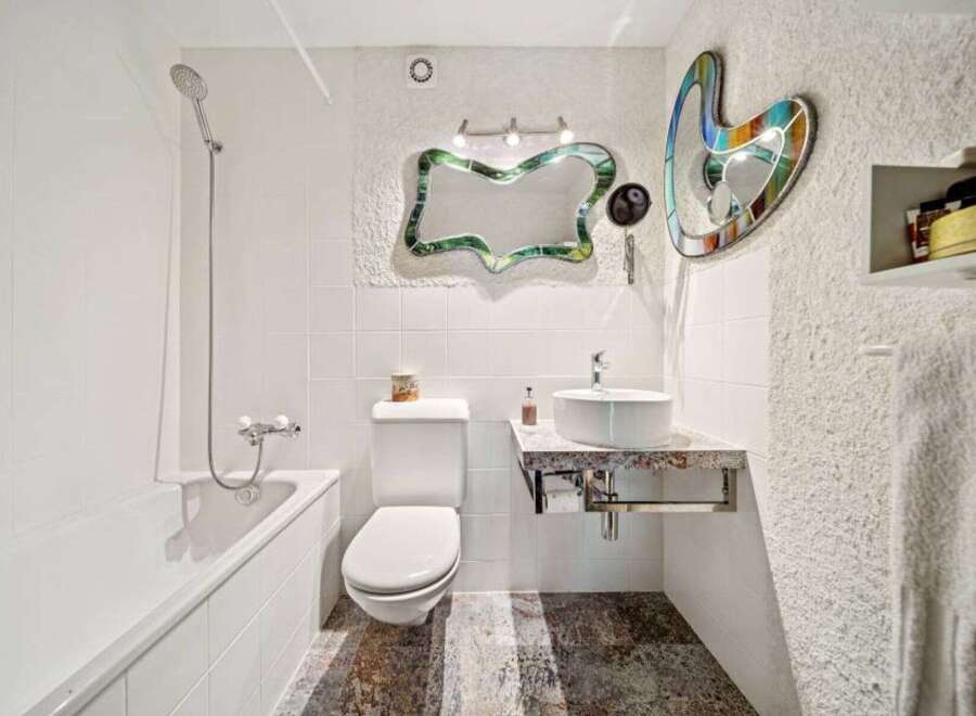 Step into this unique bathroom featuring artistic mirrors and a modern sink.