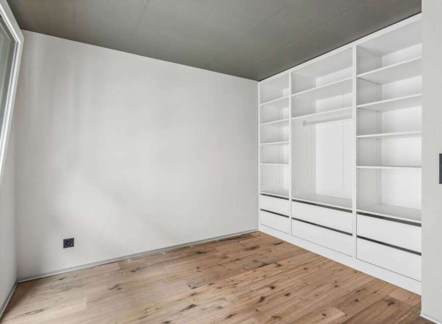 Discover the elegance of this modern space, featuring a custom-built white closet system offering ample storage.