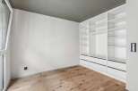Discover the elegance of this modern space, featuring a custom-built white closet system offering ample storage.