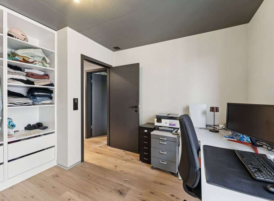 This modern home office features a sleek design with a built-in closet for ample storage.