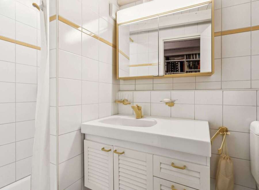 This charming bathroom features a classic design with white tiled walls and gold accents.