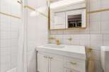 This charming bathroom features a classic design with white tiled walls and gold accents.