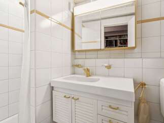 This charming bathroom features a classic design with white tiled walls and gold accents.