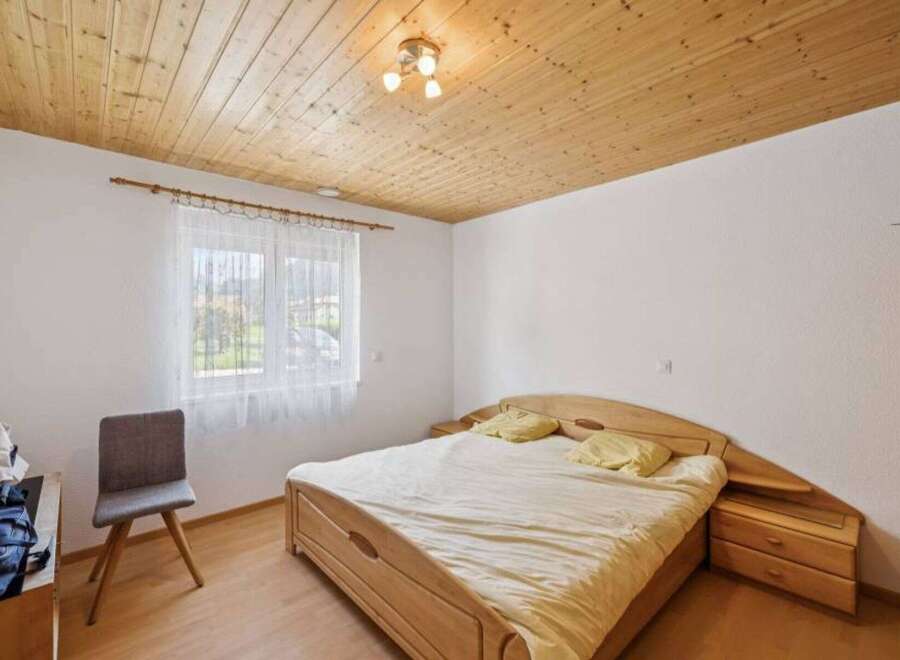 This cozy bedroom features a warm wooden ceiling and flooring, creating a welcoming atmosphere.