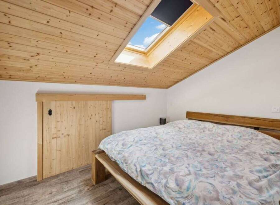 This charming bedroom features a unique sloped ceiling with a skylight, allowing natural light to flood the space.