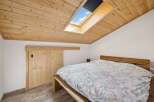 This charming bedroom features a unique sloped ceiling with a skylight, allowing natural light to flood the space.