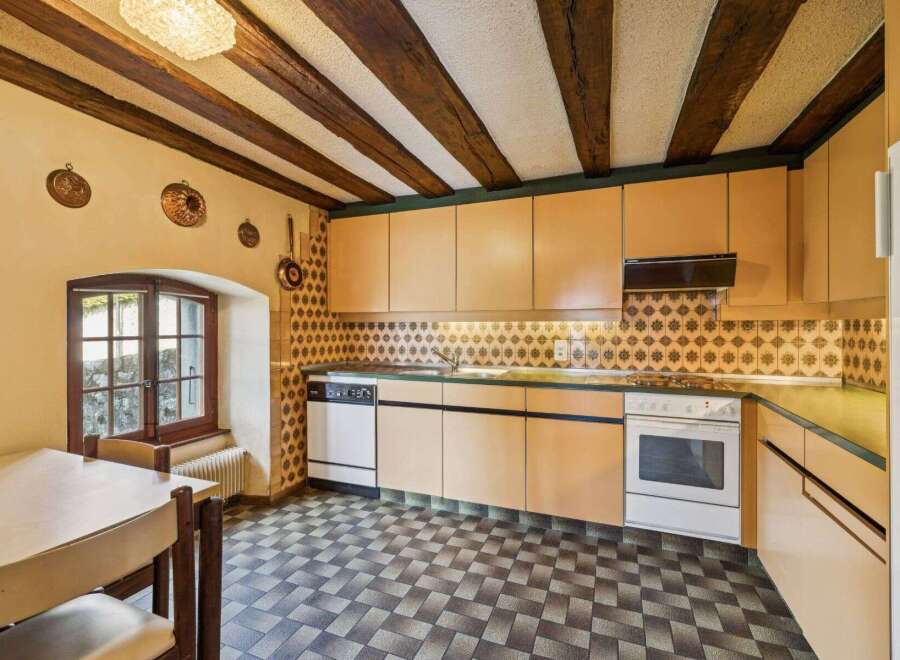 Step into this charming kitchen, featuring a unique design with exposed wooden beams and a classic tiled backsplash.