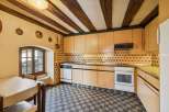 Step into this charming kitchen, featuring a unique design with exposed wooden beams and a classic tiled backsplash.