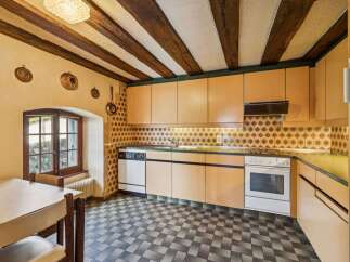 Step into this charming kitchen, featuring a unique design with exposed wooden beams and a classic tiled backsplash.