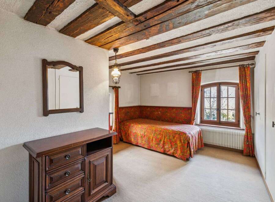 Step into this charming bedroom featuring a unique wooden beam ceiling and a cozy ambiance.