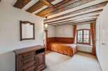 Step into this charming bedroom featuring a unique wooden beam ceiling and a cozy ambiance.