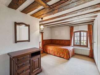 Step into this charming bedroom featuring a unique wooden beam ceiling and a cozy ambiance.