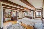 Step into a charming bedroom with rustic wooden beams and elegant design.