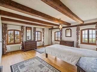 Step into a charming bedroom with rustic wooden beams and elegant design.