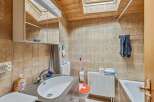 This charming bathroom features a unique design with wooden accents and a skylight, creating a bright and inviting space.