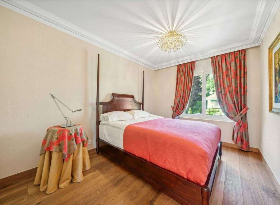 Step into this elegant bedroom, featuring a classic four-poster bed and warm wooden flooring.