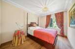Step into this elegant bedroom, featuring a classic four-poster bed and warm wooden flooring.